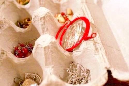 Bijoux rangés dans une boîte à œufs et colliers enroulés sur un rouleau de carton